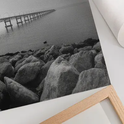 Eleganten plakat za dnevno sobo mirna pokrajina z mostom, skalnato plažo in sivim nebom