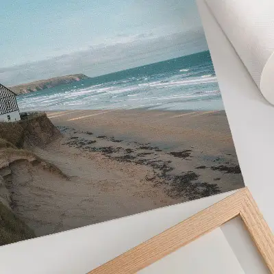 Umetniški tisk na platno plaža z valovi in hišo na pečini v pastelnih barvah