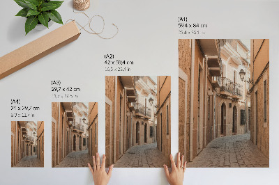 Plakat Ozka ulica, kamnite stavbe, topli odtenki