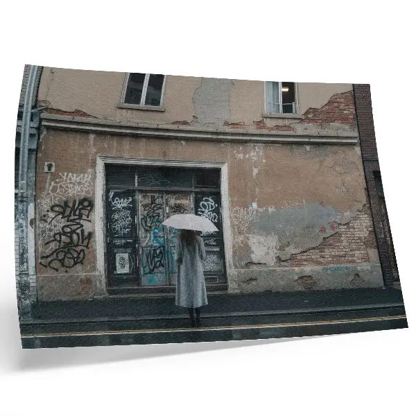 Plakat na platnu oseba z dežnikom pred zidom z grafiti